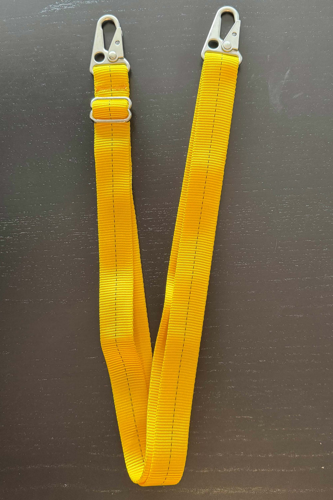 Yellow strap with metal hooks on a dark surface